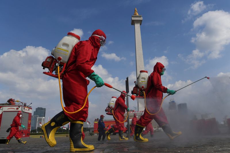 FILE PHOTO:  Firefighters wearing protective suits spray disinfectant at