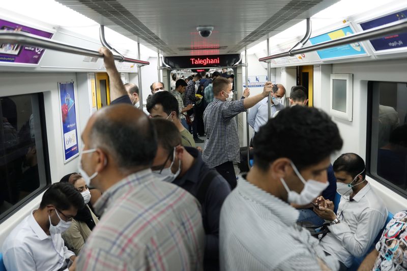 Iranians wearing protective face masks ride the metro, following the