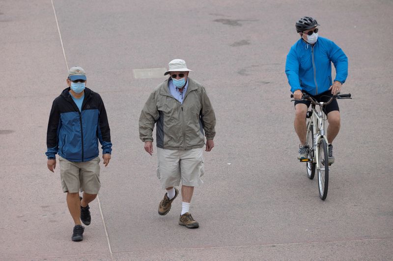 People wear face masks as they use the beach boardwalk