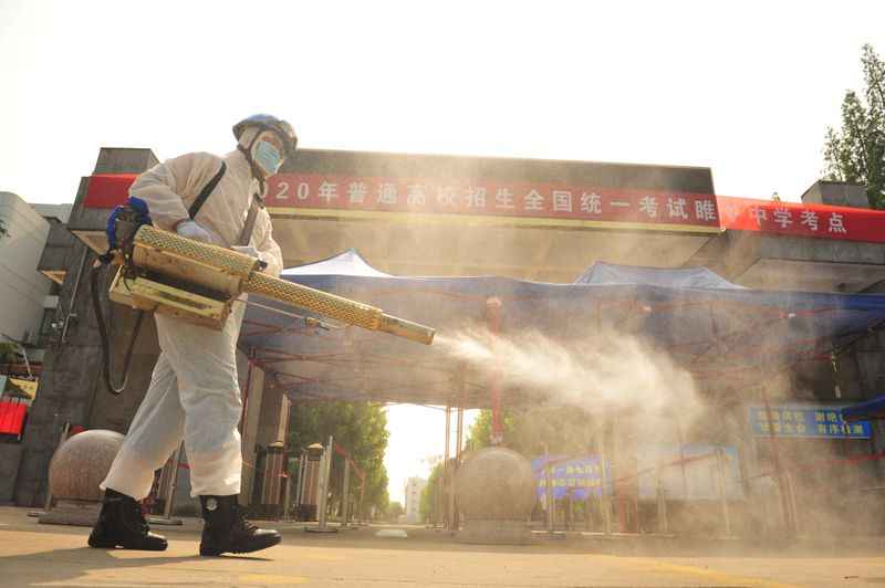 Volunteer disinfects a high school where the annual national college