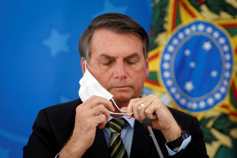 FILE PHOTO: Brazil’s President Jair Bolsonaro adjusts his protective face