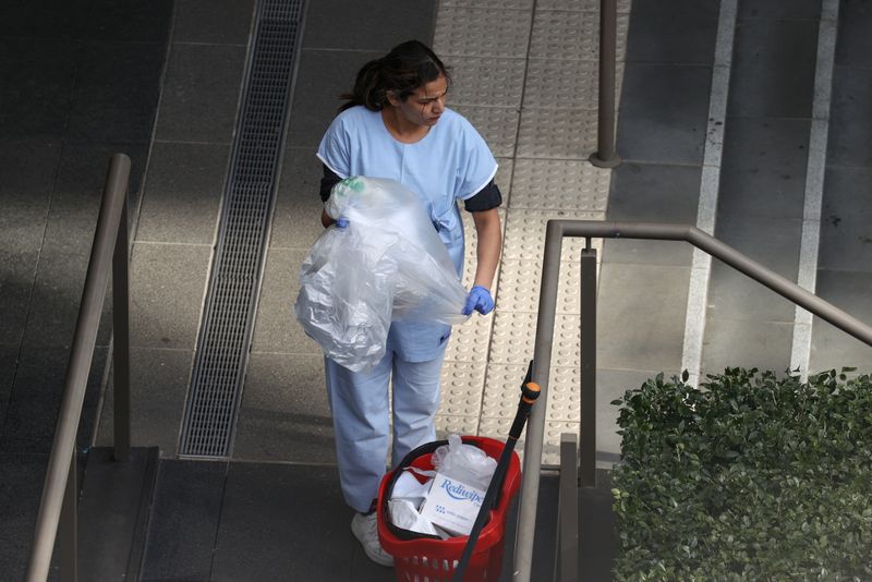 A worker disposes of waste outside a quarantine hotel in