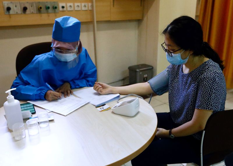 FILE PHOTO: Healthcare worker checks the tension of a volunteer