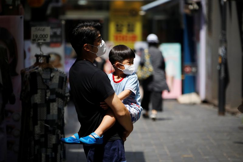 A man holds his son as they shop at Myeongdong