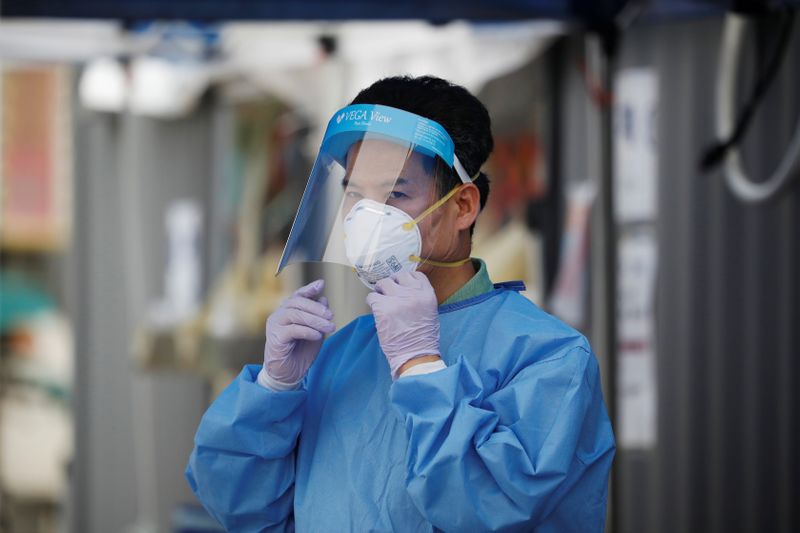 An official wearing personal protective equipment adjusts his face shield