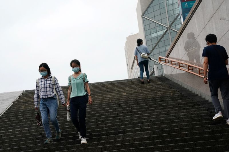 People wearing face masks walk down steps near a subway