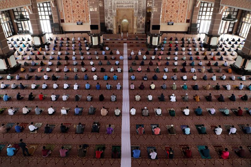 Muslims following social distancing measures pray inside a mosque, amid