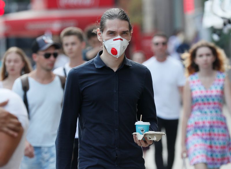 A man wearing a protective face mask crosses a street