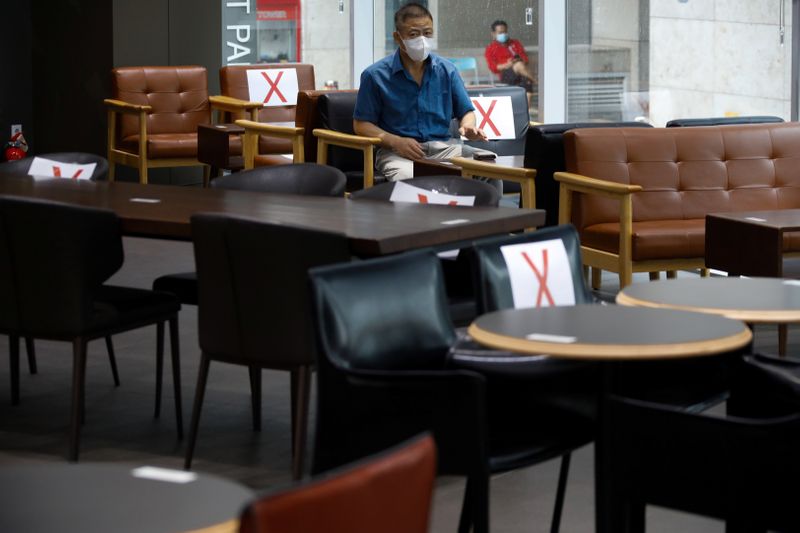 Man wearing a protective face mask sits as signs are