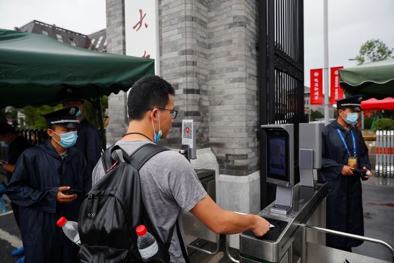 People pass facial recognition camera-controlled gates to enter Peking University