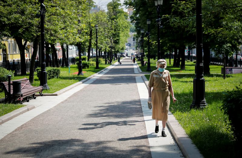 FILE PHOTO: A woman wearing a protective face mask walks