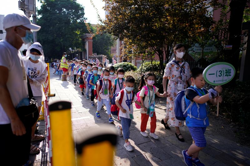 Students wearing protective face masks walk out of a primary