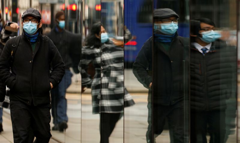 People wearing face coverings are reflected in the window of