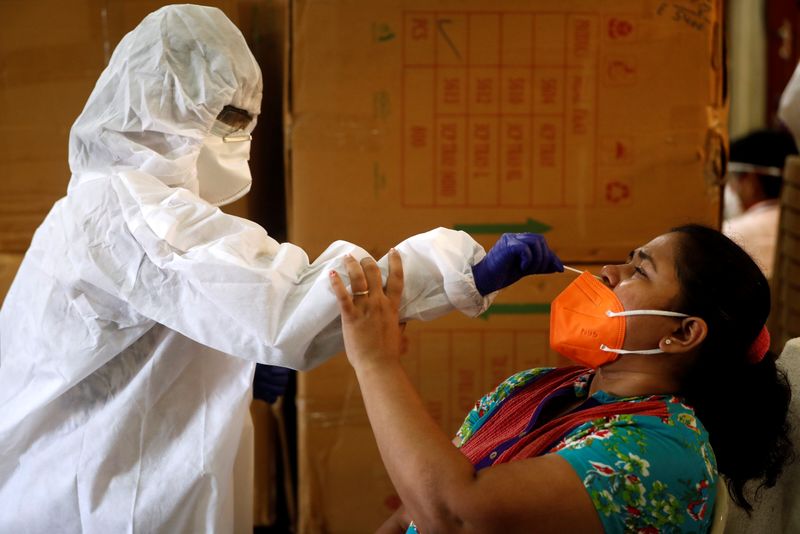 A health worker in personal protective equipment (PPE) collects a