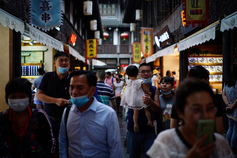 People wearing face masks walk on Jinli Ancient Street in