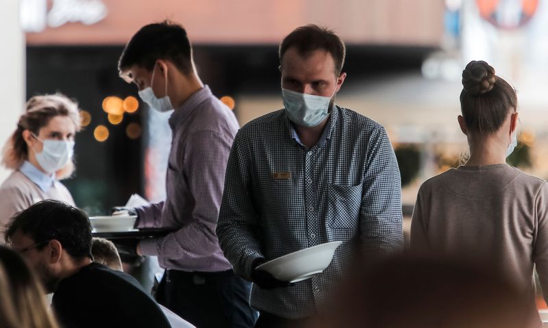 Waiters at the terrace cafe wear protective face masks in