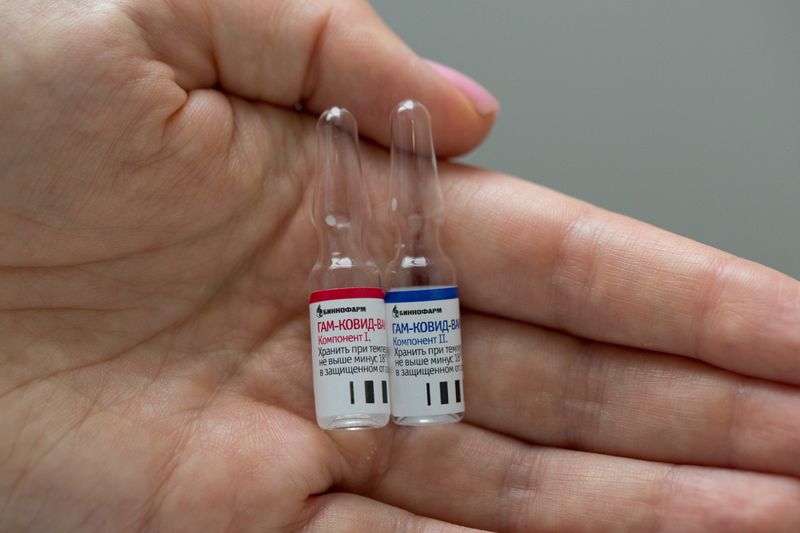 A photo shows an employee demonstrating vials with vaccine against