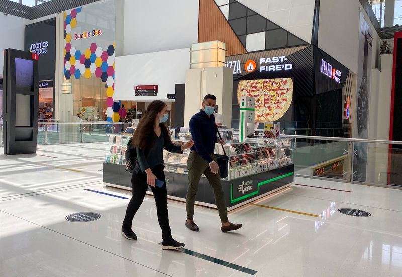 People wearing protective face masks walk at Dubai mall after