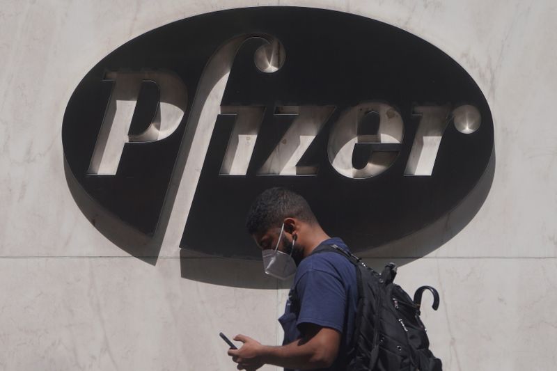 A man walks past a sign outside Pfizer Headquarters in
