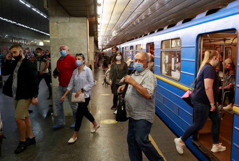 FILE PHOTO: Passengers wearing protective face masks walk at Pozniaky