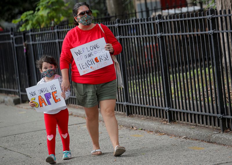 A parent and her child carry signs to protest the