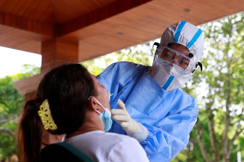 Medical worker in protective suit collects a swab sample from