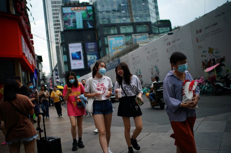 People wearing face masks walk at a shopping area in