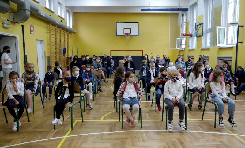 FILE PHOTO: Children listen to their school teacher’s speech during