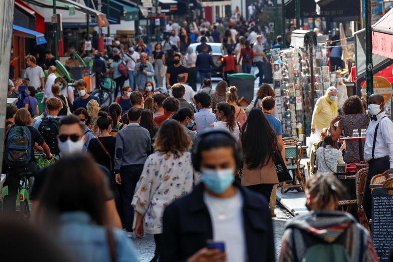 People wearing protective face masks walk in a busy street