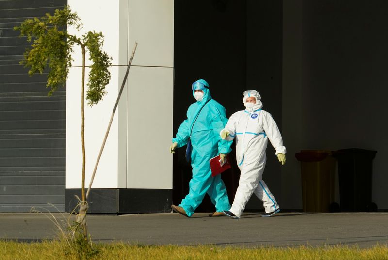 Medical specialists wearing protective gear walk outside a hospital for