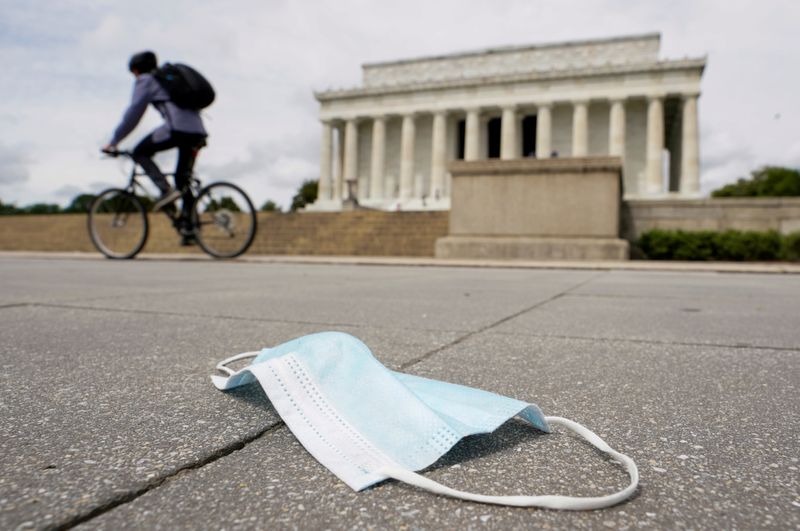 FILE PHOTO: A cyclist passes a discarded face mask in