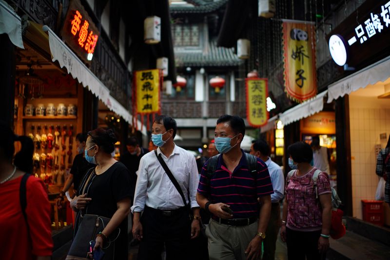 People wearing face masks walk on Jinli Ancient Street in