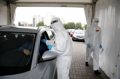 A woman wearing protective coverall, performs tests for the coronavirus