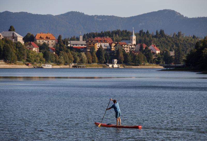 A man is seen on a standup paddleboard or SUP