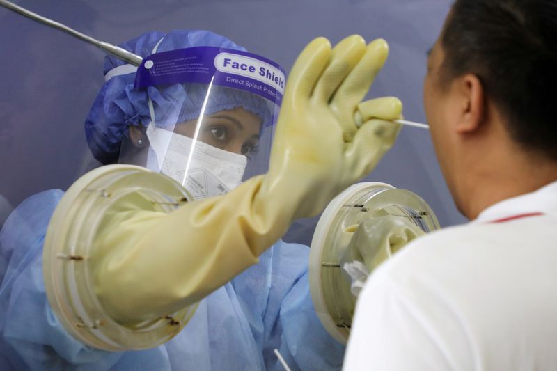 A doctor in a protective chamber takes a swab from