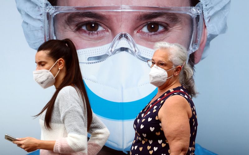 People, wearing protective face masks, walk past a dental clinic