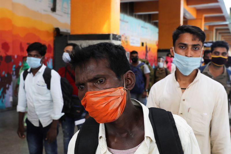 FILE PHOTO: Passengers wearing protective face masks stand in a