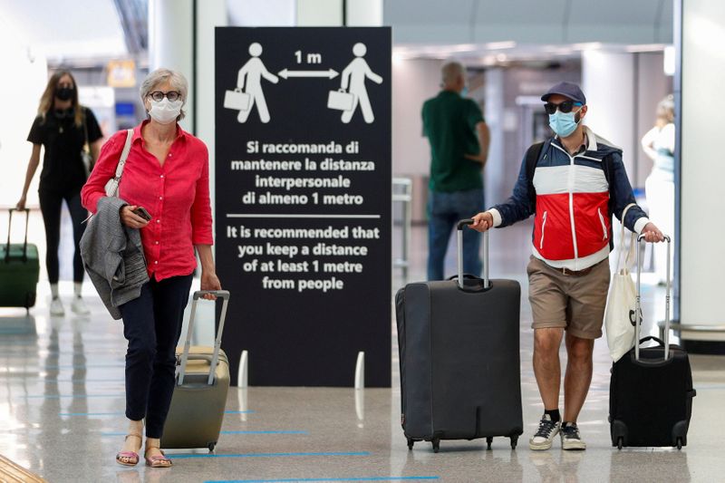 FILE PHOTO: Passengers wearing protective face masks walk at Fiumicino