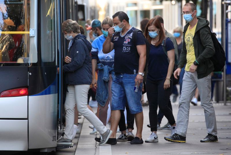 Passengers wear protective masks as they enter a tram tram