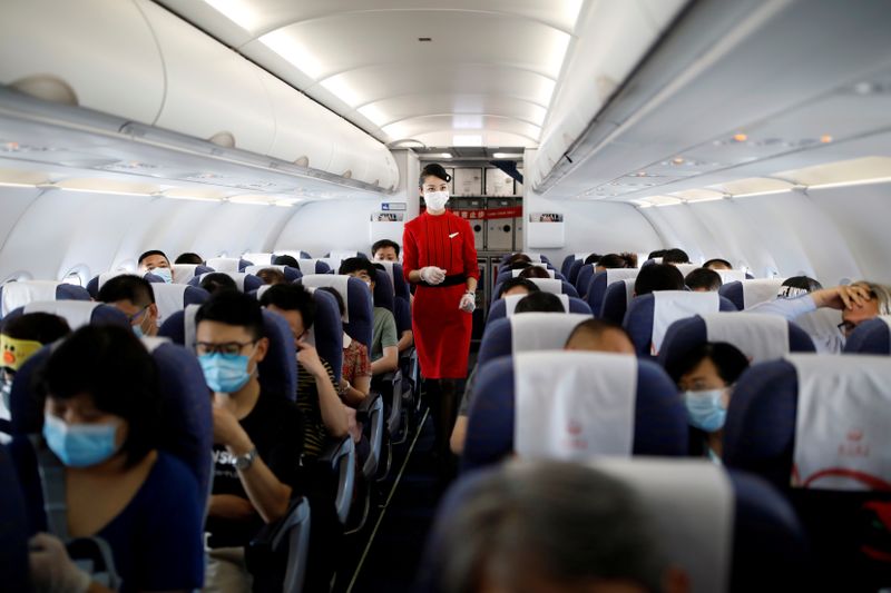 FILE PHOTO: Flight attendant walks past passengers inside an aircraft