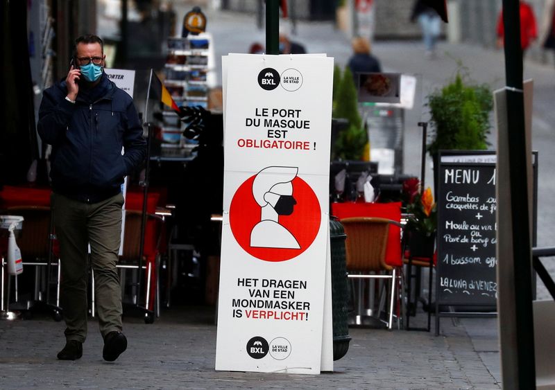 A man walks past a sign announcing the mandatory use