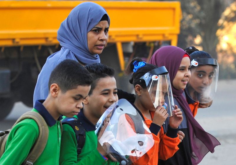 Students wearing protective face shields arrive to attend the first