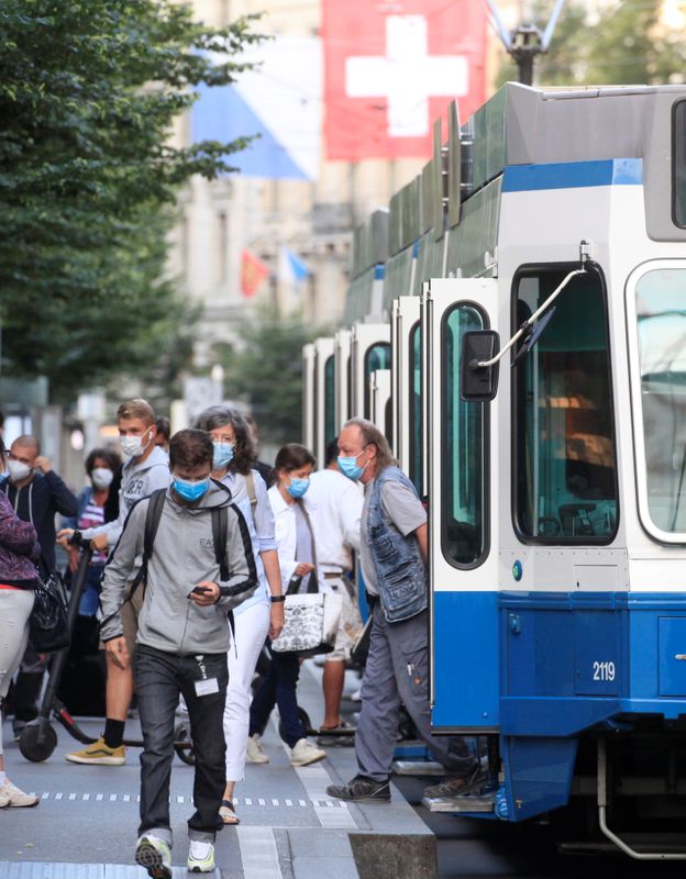 Passengers wear protective masks as they leave a tram tram