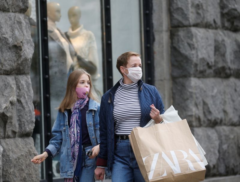 Women wearing protective face masks walk along a street in
