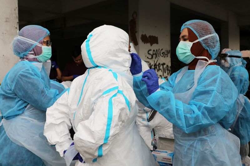 Medical workers help each other put on PPE before a