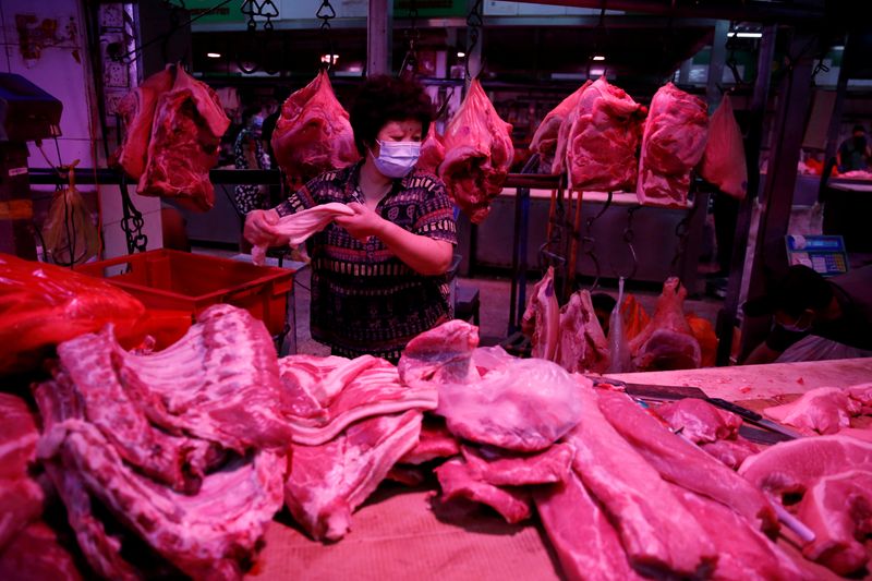 FILE PHOTO: Vendor wearing a face mask prepares pork meat