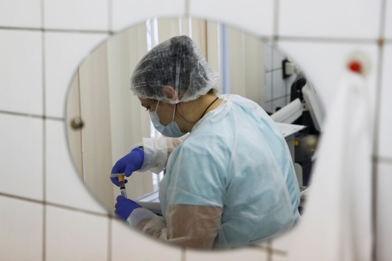 A healthcare worker is reflected in a mirror while working
