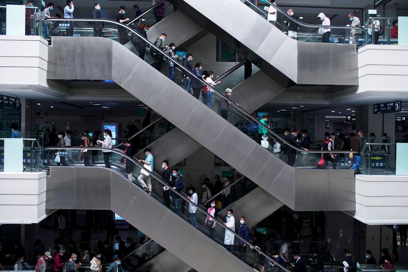 People wearing face masks stand on escalators at a hospital
