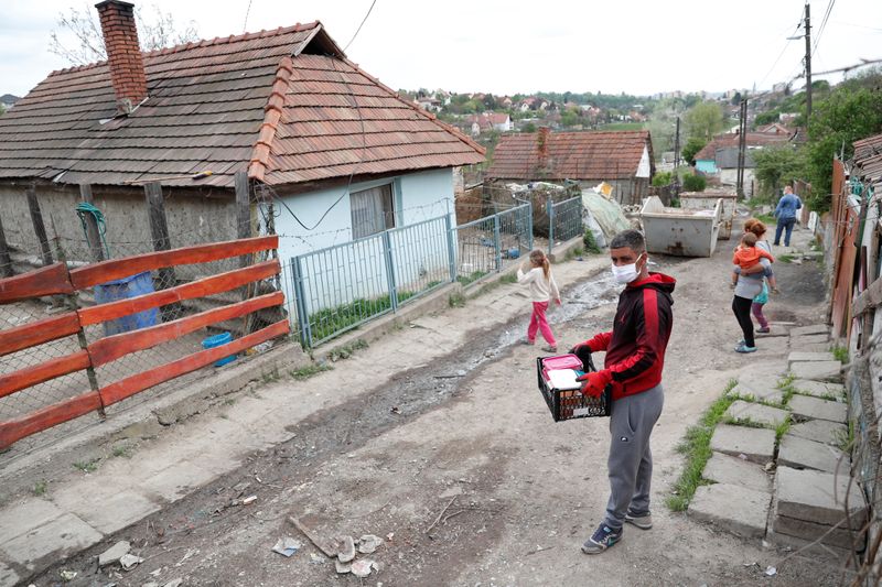 Szukup, a Roma activist carries food donation at a slum