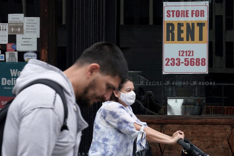 FILE PHOTO: People walk past a shuttered store in New